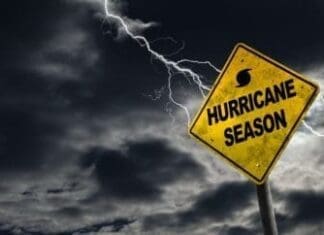 Hurricane season with symbol sign against a stormy background and copy space. Dirty and angled sign adds to the drama.
