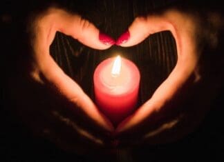 Heart Shaped Female Hands Around Burning Red Candle