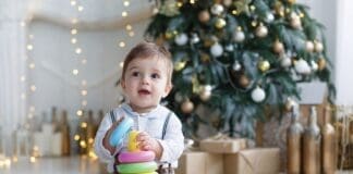 The Kid, Sitting On The Floor Near A Smart Christmas Tree, Collects A Multicolored Pyramid.