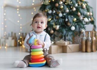 The Kid, Sitting On The Floor Near A Smart Christmas Tree, Collects A Multicolored Pyramid.