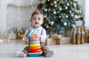 The Kid, Sitting On The Floor Near A Smart Christmas Tree, Collects A Multicolored Pyramid.