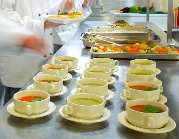 Four,chefs,working,in,a,modern,kitchen,preparing,soups