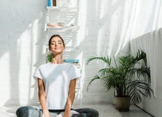 Beautiful Happy Girl With Closed Eyes Practicing Yoga In Lotus Position In Bedroom In The Morning