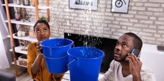 Couple Using Bucket For Collecting Water Leakage From Ceiling