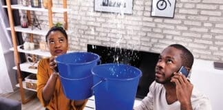 Couple Using Bucket For Collecting Water Leakage From Ceiling
