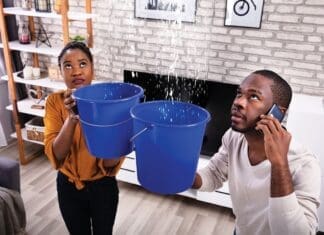 Couple Using Bucket For Collecting Water Leakage From Ceiling