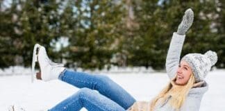 Young Woman Falling Down While Ice Skating At Winter Rink