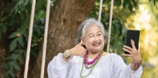 Elderly Woman Relaxing On A Swing While Using A Tablet In A Serene Outdoor Setting