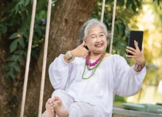 Elderly Woman Relaxing On A Swing While Using A Tablet In A Serene Outdoor Setting