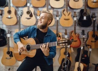Young Man Plays On Acoustic Guitar In Music Store