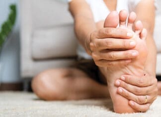 Asian Woman Feeling Pain In Her Foot At Home