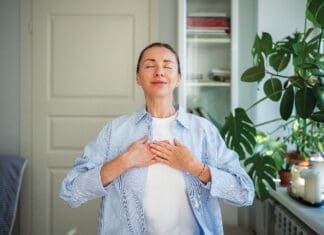 Relaxed Smiling Woman Meditates With Hands On Chest, Practice Breathing Exercises At Home. Self Care