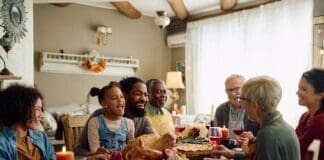 Cheerful,multiracial,family,enjoying,in,conversation,during,thanksgiving,meal,at
