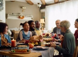 Cheerful,multiracial,family,enjoying,in,conversation,during,thanksgiving,meal,at