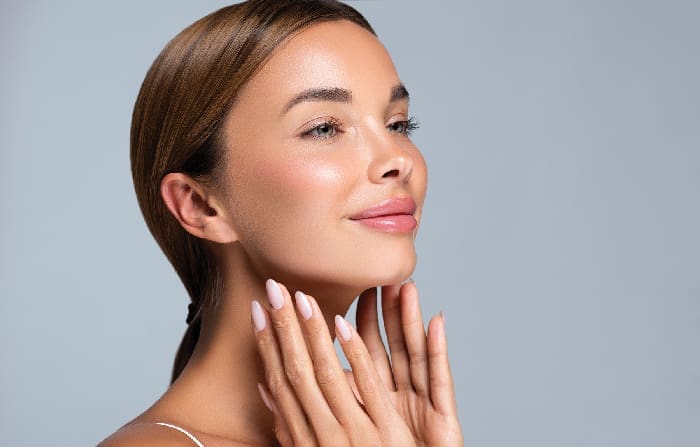 Gorgeous, Young Woman With Clean, Fresh Skin Is Touching The Face. Light Smile On The Perfect Face. Cosmetology Manicure.