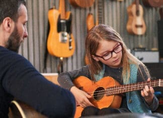 Dad,teaching,guitar,and,ukulele,to,his,daughter.little,girl,learning