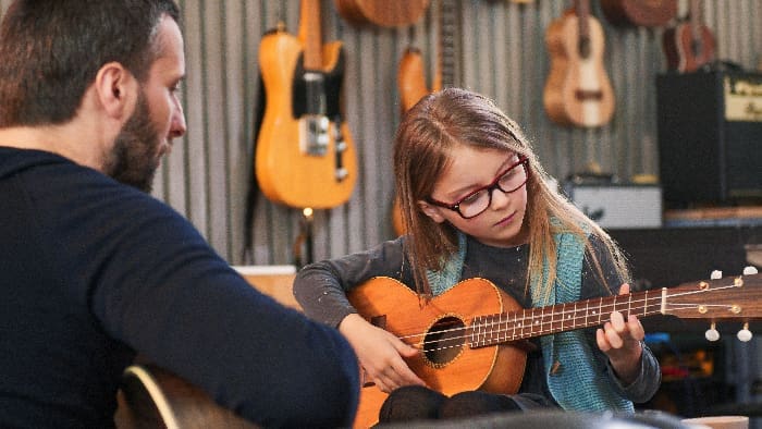 Dad,teaching,guitar,and,ukulele,to,his,daughter.little,girl,learning