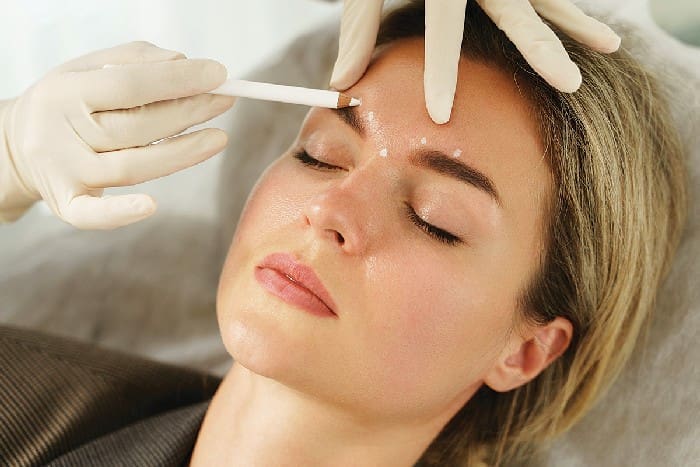 Doctor Making Marks On Client's Face Before Filler Injection