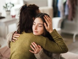 Teenage Girl Hugging Her Mother At Home.