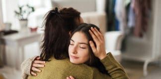 Teenage Girl Hugging Her Mother At Home.