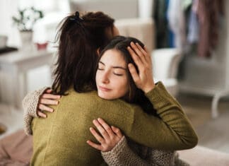 Teenage Girl Hugging Her Mother At Home.