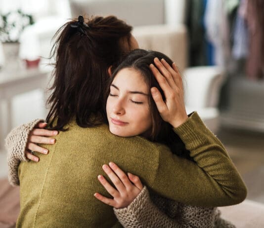 Bring Hope Now: Local Nonprofit Aims to Solve Youth Mental Health Crisis Teenage Girl Hugging Her Mother At Home.