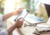 Summer Occupancy Is Peaking. Is Your Community Ready? Businessman Hand Using Digital Tablet Working With Laptop Computer And Smartphone In Coworking Space. Urban Lifestyle With Modern Electronic Devices. Internet Of Things And Online App Concepts