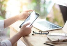 Summer Occupancy Is Peaking. Is Your Community Ready? Businessman Hand Using Digital Tablet Working With Laptop Computer And Smartphone In Coworking Space. Urban Lifestyle With Modern Electronic Devices. Internet Of Things And Online App Concepts