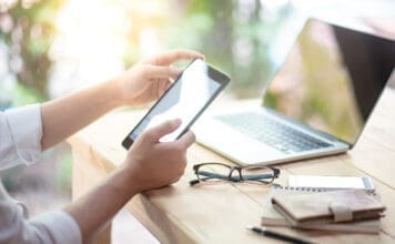 Summer Occupancy Is Peaking. Is Your Community Ready? Businessman Hand Using Digital Tablet Working With Laptop Computer And Smartphone In Coworking Space. Urban Lifestyle With Modern Electronic Devices. Internet Of Things And Online App Concepts